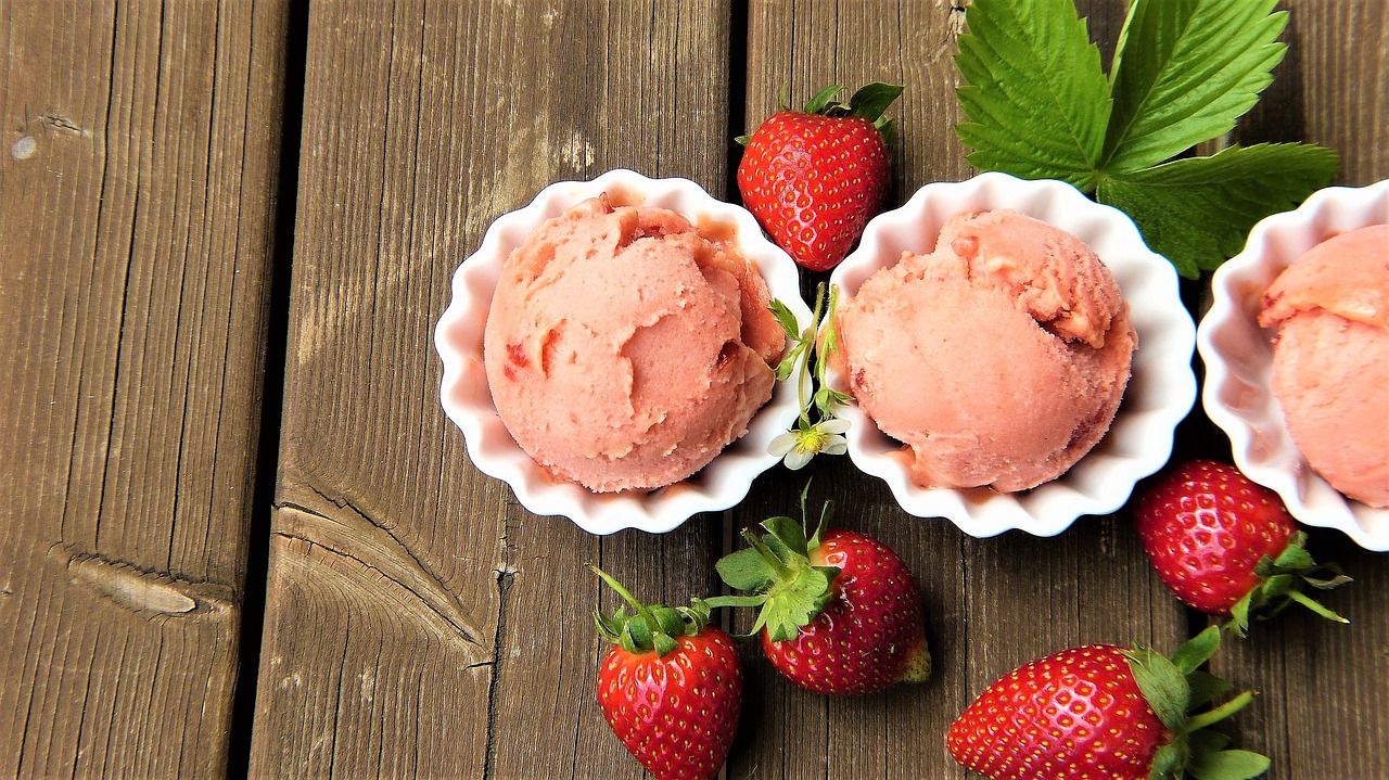 Three scoops of strawberry ice cream and some strawberries